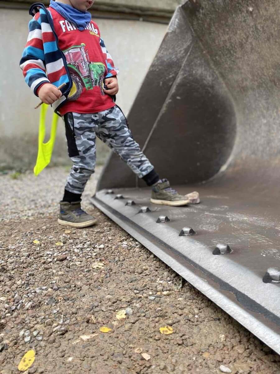 Kind stellt Fuß in Baggerschaufel